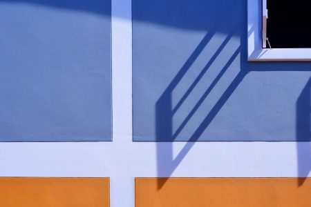 Sunlight and shadow on surface of white wooden window with blue and orange painted wall decoration background, exterior architecture concept